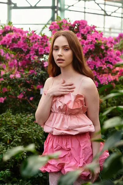 In a lush greenhouse filled with blooming flowers, a young woman captivates with her beauty. — Stock Photo