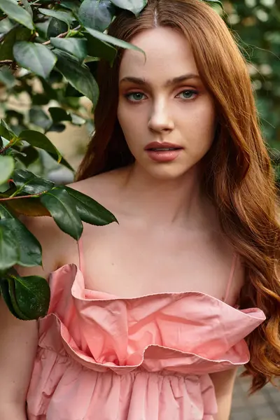 A young woman interacts gracefully with vibrant plants in a tranquil greenhouse oasis. — Stock Photo