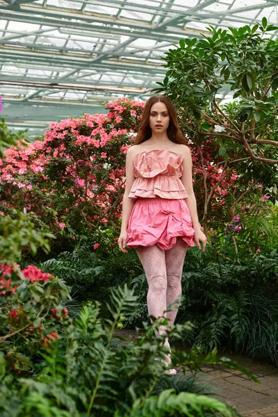 A young woman strolls through a vibrant greenhouse in her playful outfit. — Stock Photo