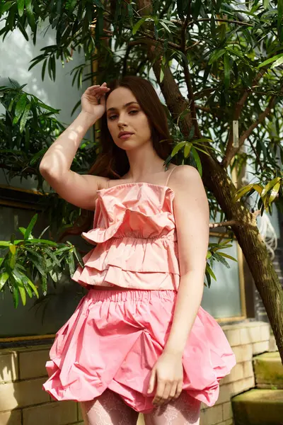 A lovely young woman poses gracefully among lush plants in a vibrant greenhouse. — Stock Photo