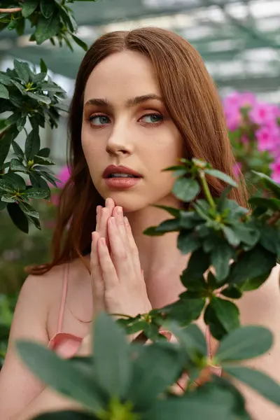 A young woman finds tranquility amid lush plants and blooming flowers in a greenhouse. — Stock Photo