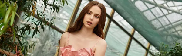 Young beautiful woman explores a lush greenhouse, surrounded by vibrant plants and serene beauty. — Stock Photo