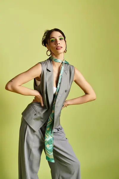Confident young woman poses elegantly in stylish gray attire, highlighting vibrant accessories. — Stock Photo