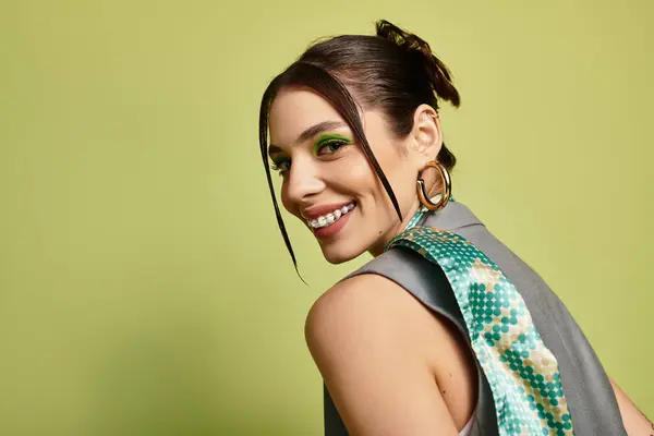 A young beautiful woman with striking makeup smiles joyfully while showcasing her fashion sense. — Stock Photo
