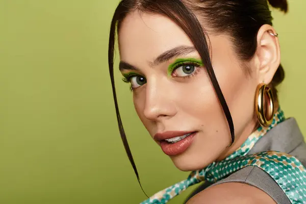 A young beautiful woman showcases a stunning look with bold green makeup, radiating confidence. — Stock Photo