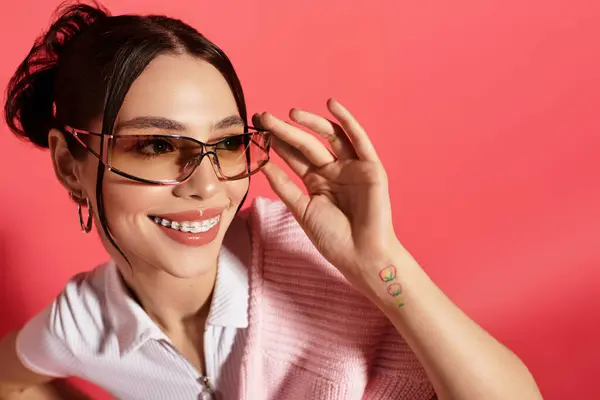 Una joven alegre posa confiadamente con gafas de sol de moda y un atuendo elegante. - foto de stock