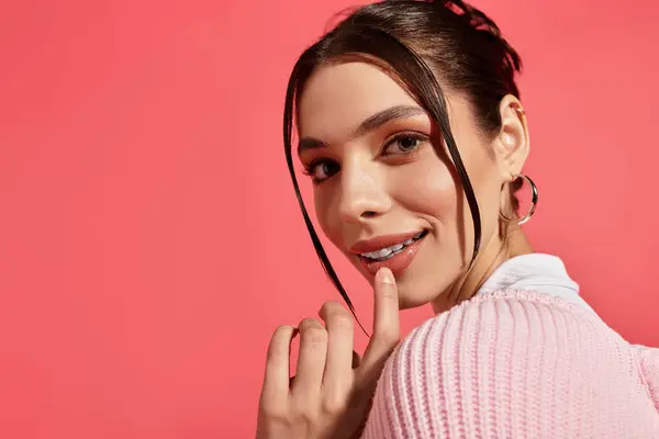 Una joven encantadora toca juguetonamente sus labios, irradiando calidez y encanto a la cámara. - foto de stock