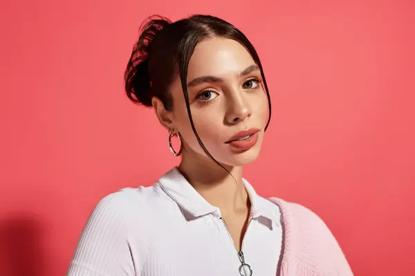 Uma bela jovem posa, destacando suas características e roupas contra um fundo rosa. — Fotografia de Stock