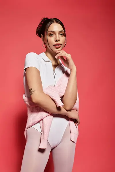 La joven hermosa mujer muestra confianza mientras sostiene suavemente un suéter rosa, irradiando encanto. - foto de stock