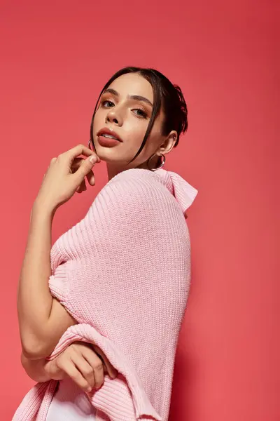 A graceful young woman smiles softly in a stylish pose against a bright pink wall. — Stock Photo
