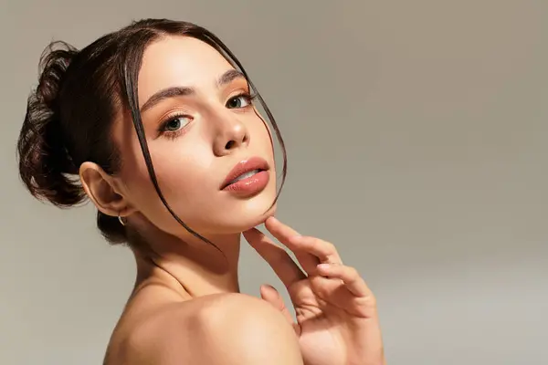 Charme rayonnant, une jeune belle femme pose gracieusement avec une touche délicate à son visage. — Photo de stock