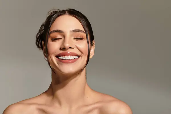 A young woman captivates with a genuine smile in a soft, neutral setting. — Stock Photo