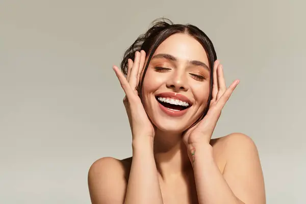 Bright smile radiates joy as girl poses with graceful hands on her face in a serene atmosphere. — Stock Photo