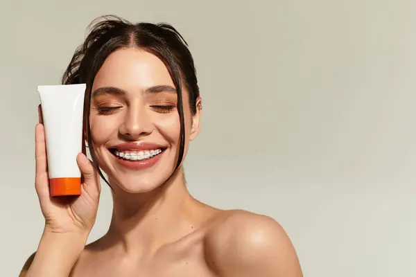 In a relaxed setting, a young beautiful woman enjoys her skincare ritual, radiating happiness. — Stock Photo