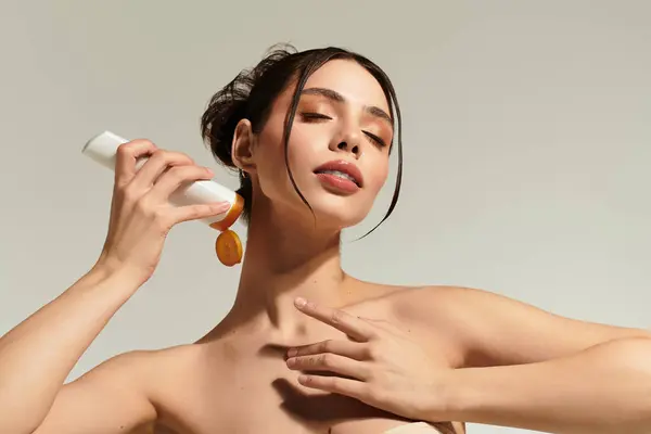 Beautiful young woman applies skincare product to her neck, showcasing confidence and elegance. — Stock Photo