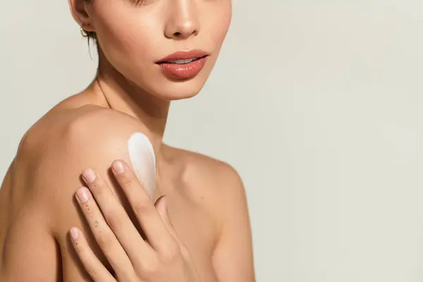 Young woman applies cream to her shoulder, savoring a moment of self care and peace. — Stock Photo