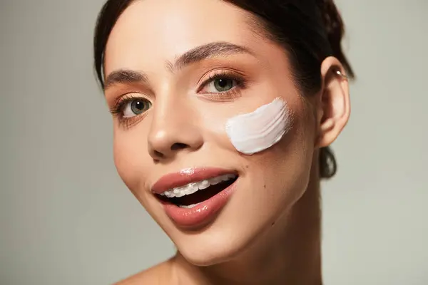 Senhora alegre goza de sua rotina de cuidados com a pele, realçando sua beleza natural com um rosto fresco de creme. — Fotografia de Stock