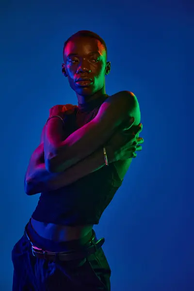 A confident young man poses dynamically, showcasing stylish attire and vibrant lighting. — Stock Photo