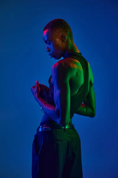 Un joven afroamericano exhibe su elegante atuendo en un entorno vibrante. - foto de stock