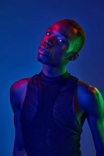 A young man dresses in innovative attire, exuding confidence against a striking colorful backdrop. — Stock Photo