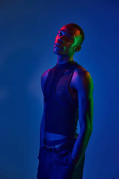 A confident young african american man shines in vibrant attire with striking lighting effects. — Stock Photo