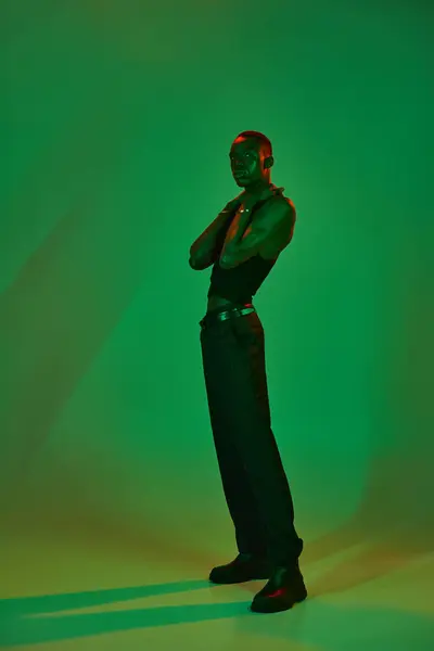 A young african american man elegantly poses in stylish attire against a striking green backdrop. — Stock Photo