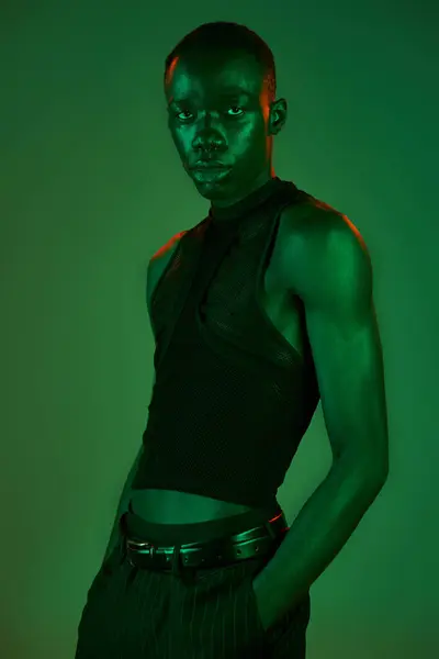 Young african american man poses confidently in stylish clothes against a bold green backdrop. — Stock Photo