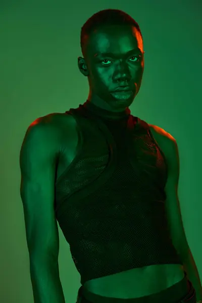 Stylish young man displays confident attitude in striking attire highlighted by vivid green lights. — Stock Photo