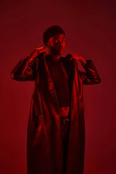 A young African American man poses stylishly in stunning red light. — Stock Photo