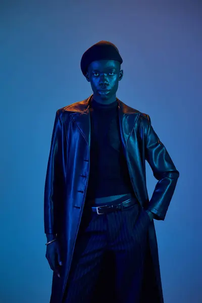 A stylish young african american man poses confidently in bold attire, lit by cool blue tones. — Stock Photo