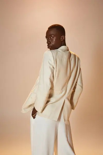 Confident young african american man in a chic outfit poses gracefully against a soft backdrop. — Stock Photo