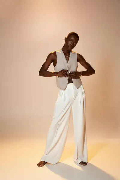 A stylish young African American man poses confidently against a soft backdrop, radiating charisma. — Stock Photo