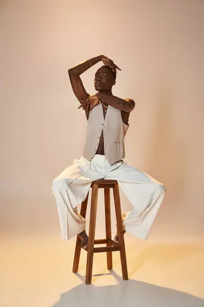 A young African American man showcases his style and charisma while posing on a wooden stool. — Stock Photo