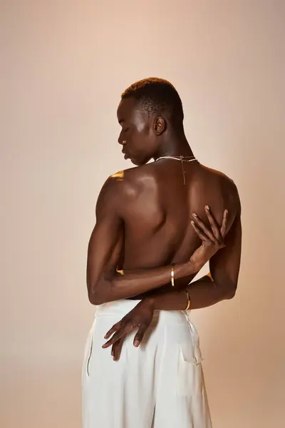 A young african american male dressed in stylish attire exudes confidence against a soft backdrop. — Stock Photo