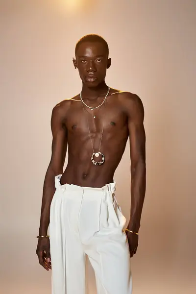 Confident young man in stylish attire poses against a minimal backdrop, exuding charm and elegance. — Stock Photo