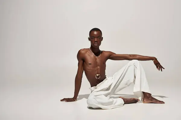 Un joven afroamericano deslumbra con vibrante atuendo blanco, atrayendo la atención. - foto de stock