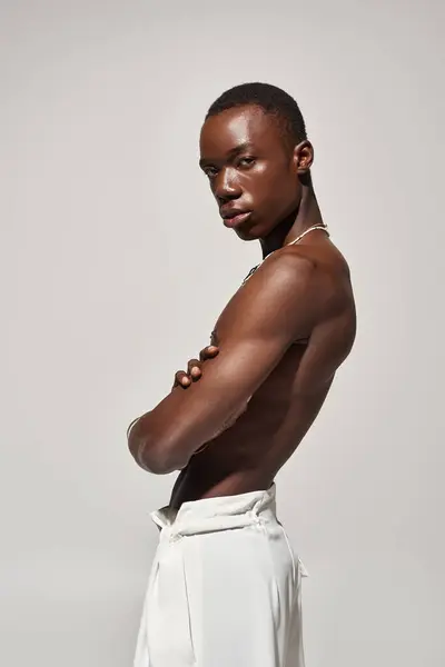 A young african american man stands confidently with crossed arms in stylish, vibrant attire. — Stock Photo