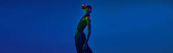 A young african american man poses confidently in stylish attire against a bright blue background. — Stock Photo