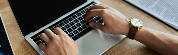 A focused person types on a laptop in a modern office, surrounded by notes. — Stock Photo