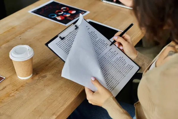 Individuel examine avec diligence la paperasserie au milieu d'un espace de travail dynamique, montrant son dévouement aux tâches. — Photo de stock