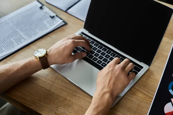 Hands type diligently on a laptop while organized paperwork rests nearby during busy office hours. — Stock Photo