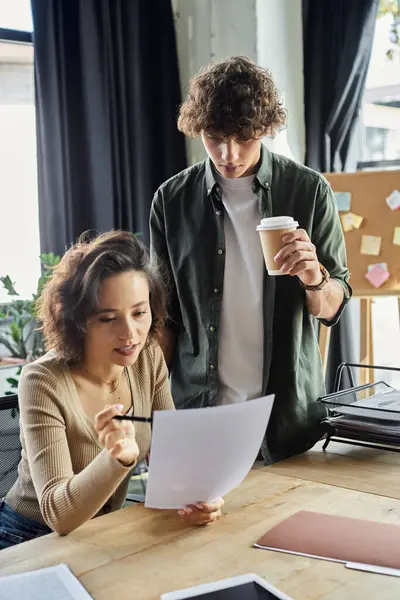 A man and woman engage in a productive discussion over documents at their shared workspace. — Stock Photo