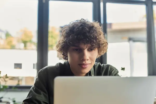Una persona concentrata lavora su un computer portatile in un ufficio luminoso e pieno di piante. — Stock Photo