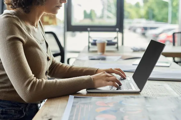 A person focuses on their laptop in an organized workspace with documents around. — Stock Photo