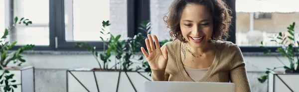 Una felice onda professionale sul suo schermo durante una riunione virtuale in uno spazio di lavoro vibrante. — Foto stock