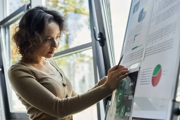 A committed worker in an office carefully studies detailed charts and reports during the day. — Stock Photo