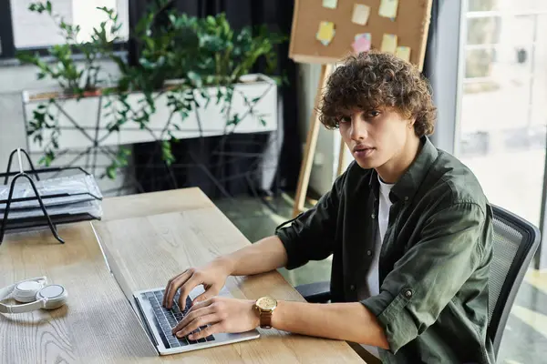 Un animado espacio de trabajo muestra a una persona joven enfocada en tareas en una computadora portátil, mostrando dedicación. - foto de stock
