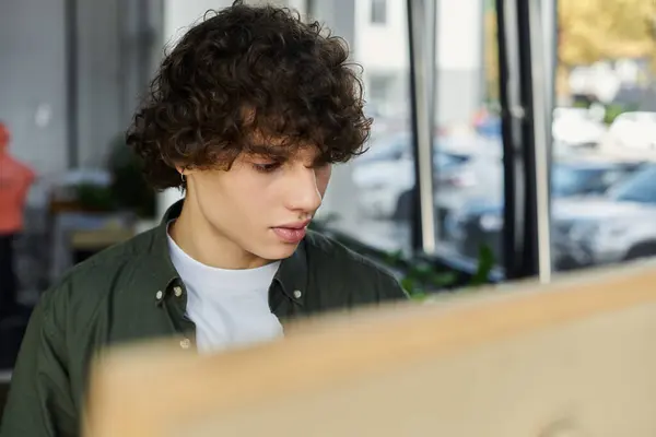 A young person focused on work in a bright, modern office. — Stock Photo