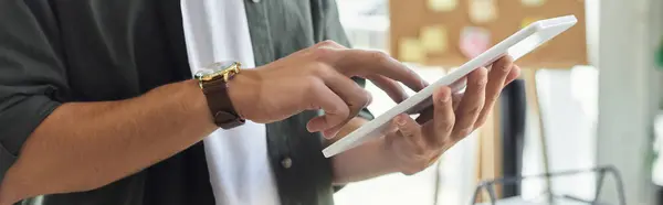 A person uses a tablet for work tasks, showcasing dedication in a contemporary office environment. — Stock Photo