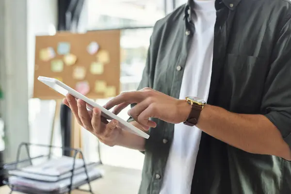 A person interacts with a tablet in a bright office space, showcasing dedication to efficient work. — Stock Photo